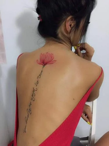 Tatuaj fine line cu floare roșie și text pe coloană