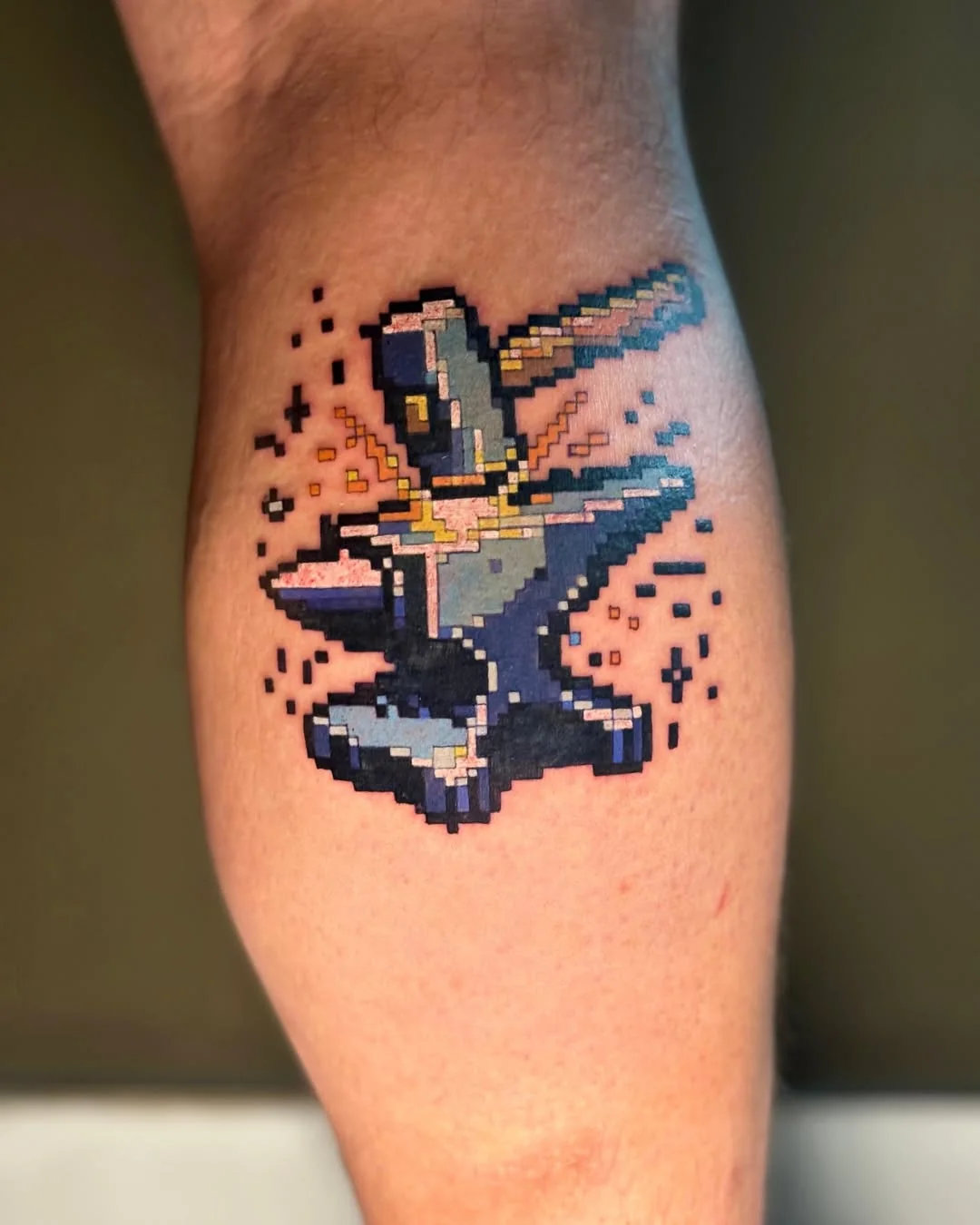 Tatuaj pixel art cu nicovală și ciocan pe gambă