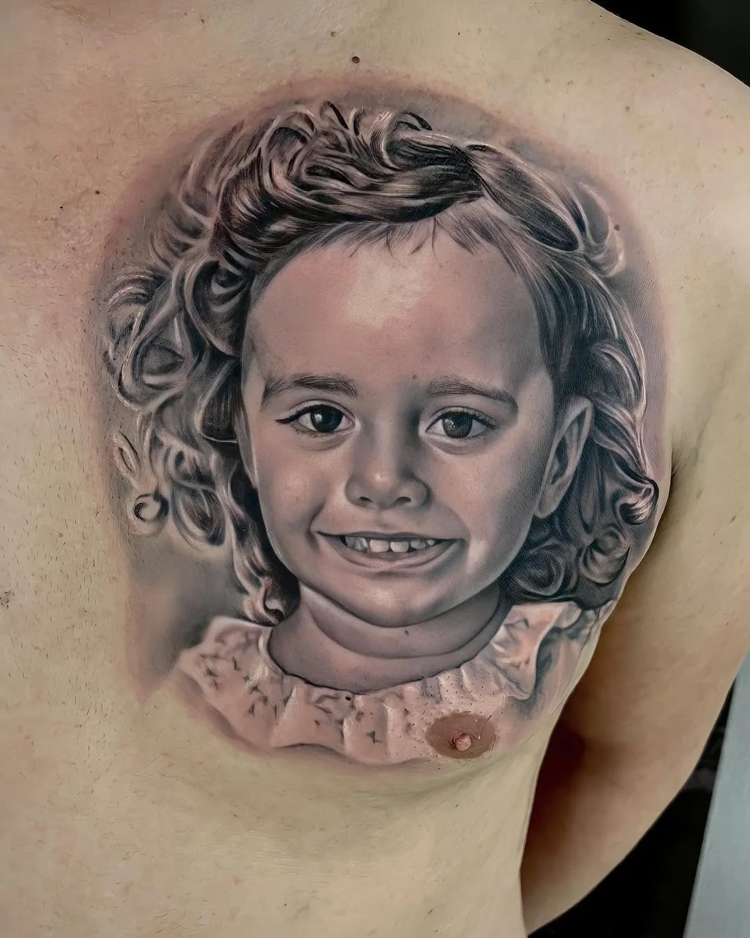 Tatuaj realist black and grey cu portret de copil care zâmbește