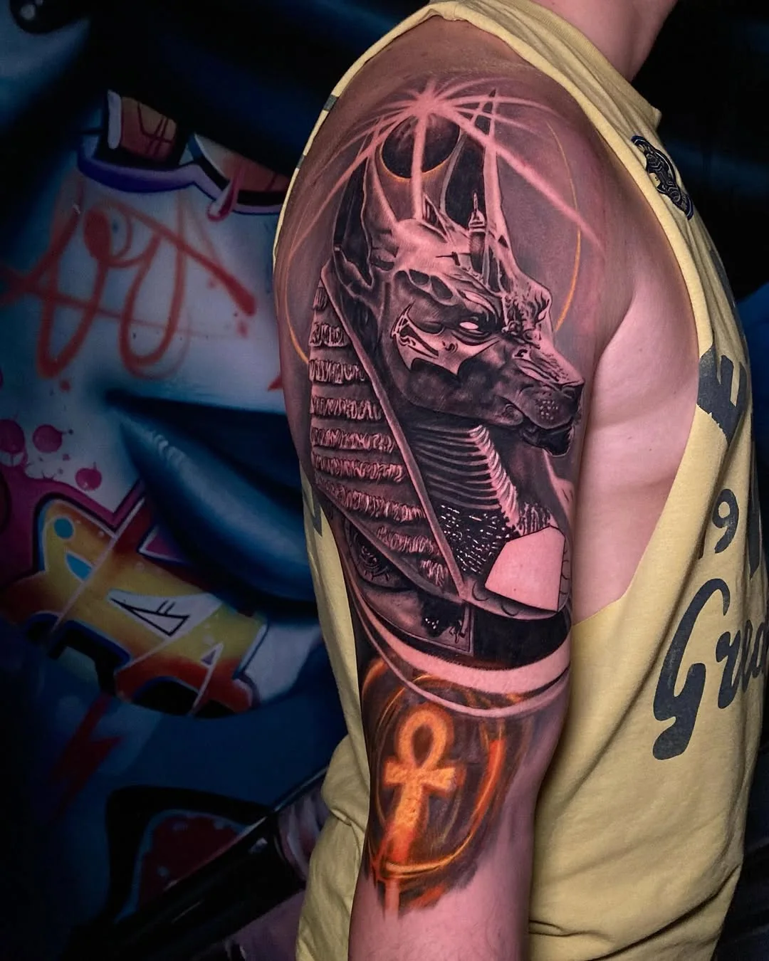 Tatuaj color cu Anubis și simbolul ankh pe umăr și braț