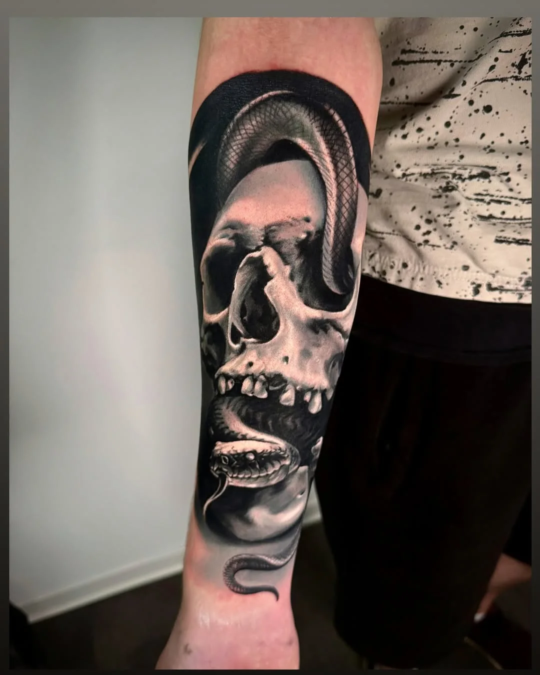 Tatuaj realist black and grey cu craniu și șarpe pe antebraț