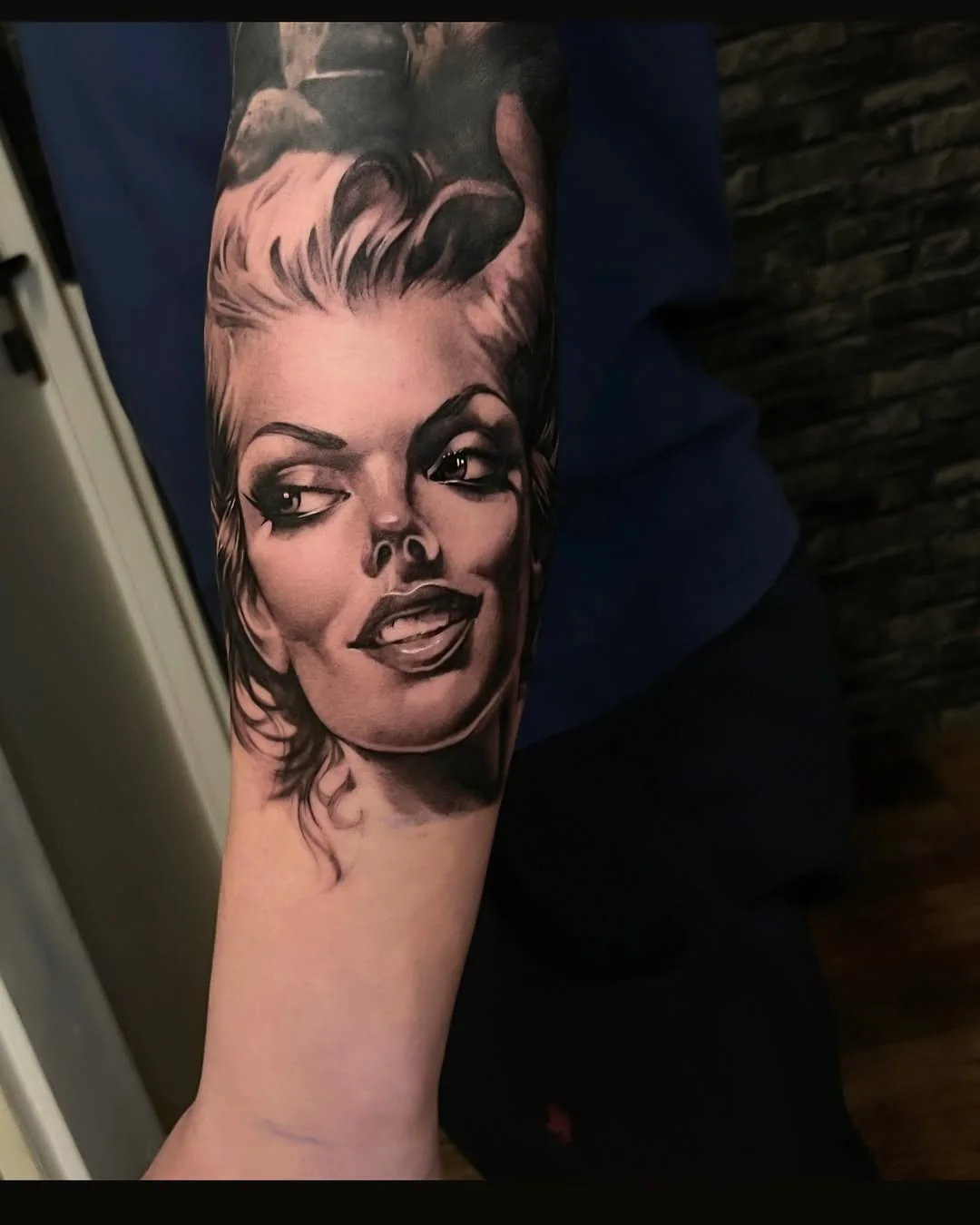 Tatuaj realist black and grey cu portret de femeie în stil pin-up pe antebraț