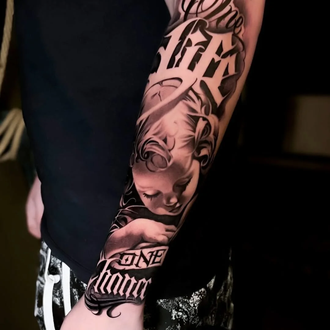 Tatuaj black and grey cu portret și lettering pe antebraț